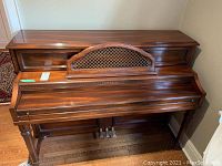 Front view of the upright piano showing wooden finish and music rack with lattice design.