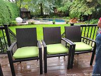 Front view of three chairs with green cushions on a wet deck