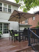 Full view of patio set on deck showing table, chairs, and beige umbrella