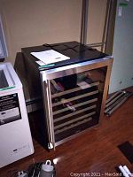 Front view of wine cooler with closed glass door, stainless steel trim and top paperwork