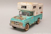 Front angle showing turquoise truck body, cream camper with windows and visible rust.