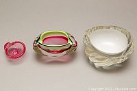 Top view of three Mid-Century Modern art glass pieces: small red textured bowl, medium pink and green glass piece, large clear bowl with white interior and texture.