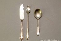 Three sterling silver cutlery pieces laid side by side showing their front sides including a butter knife, fork, and spoon.