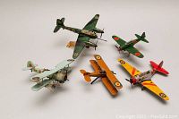 Five metal model airplanes arranged together showing different WW1 and WW2 military markings and colors.