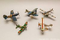 Five metal WWI and WWII model airplanes displayed on clear stands with various national markings including US, French, and German.