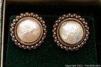 Close-up of one clip-on earring showing a central rounded faux pearl and detailed beaded silver border.