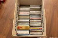 Box of assorted music CDs showing titles and artist names including Elvis Presley boxed set, Bob Marley, Sting, Garth Brooks, Bonnie Raitt, Rolling Stones, Elton John, Bruce Cockburn among others.