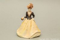 Front view of Coalport Beau Monde Berenice porcelain figurine showing detailed pale yellow dress, black bodice, and peach hat.