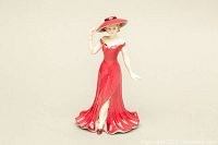Front view of Coalport porcelain figurine showing woman in red gown and wide-brimmed hat.