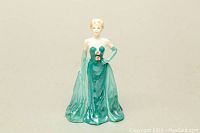 Front view of a porcelain figurine of a woman in a green strapless gown with gloves.