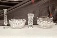 Front view of four cut crystal items including pedestal bowl, two bud vases, and a mid-sized bowl, showing clear detail of cut patterns and shapes.