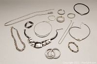 Multiple costume jewelry pieces including chunky necklaces, bangles, stretchy bracelets, and a ladies belt arranged on a white surface.