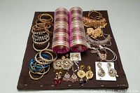 Overview of all parts of the lot showing bangles, earrings, and necklaces arranged on a dark mat