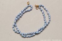 Double strand baby blue dyed freshwater pearl bracelet displayed laid out flat. Clasp is visible showing 10kt gold spring ring closure.