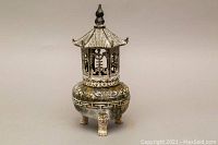 View of the assembled carved stone pagoda incense burner with three legs, decorative detailing, and finial on the lid.