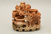 Front angled view showing intricate floral carving and multiple small jug-shaped openings.