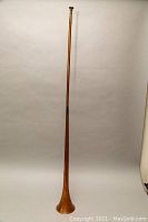 Full-length view of copper trumpet standing upright against white background