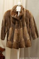 Front view of the muskrat fur jacket on a mannequin, showing button closure and collar.