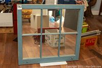 Front view of the vintage window pane style framed mirror resting against boxes and furniture, showing overall condition and distressed blue frame.