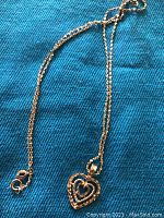 Full view of gold necklace laid out with double heart pendant and spring ring clasp visible.
