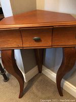 Front view showing drawer and bowed legs with a warm brown pine finish.