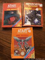 Three boxed Atari 2600 games together on table: Star Raiders, Asteroids, and Yars' Revenge. All include original box art and instruction sheets.