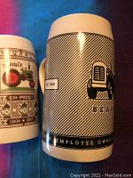 Closeup of one stein with black and white stripe and tractor design, dated 2008, showing text 'Family Run Employee Owned'.