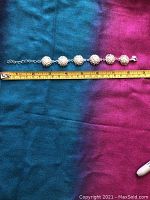 Full view of silver bracelet with measuring tape showing length about 7.5 inches.