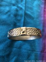 Front angle view of silver bangle bracelet showing raised Coach C pattern and clasp detail.