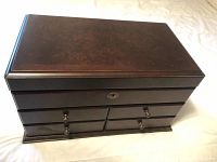 Top view of the closed wooden jewelry box showing the inlaid wood design on the lid and smooth polished finish.