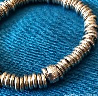Close-up of the silver stretch bracelet showing the rounded disc beads and the engraved 'LINKS LONDON' central bead.