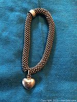 Full view of stretchy beaded bracelet with heart charm on blue fabric background