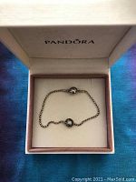 Bracelet in box showing full view of tubular silver chain and bead.