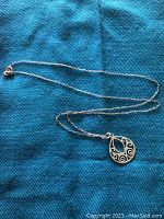 Full view of necklace with pendant laid on a turquoise fabric.