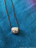 Close-up of the barrel-shaped bead pendant which is sparkly and textured.