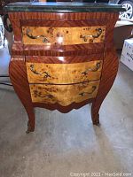 Front view of bombe chest showing three drawers with burl veneer panels and mahogany framing topped by green marble