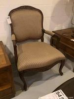 Full view of the wood side chair showing the upholstered seat, back, and curved leg design along with the carved floral top rail.