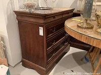 Side angle of chest showing dark wood, carved details, and overall shape.