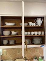 Open cabinet displaying the Noritake china set Allison pattern including various dishes and cups.