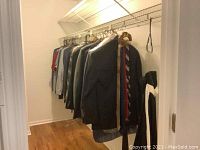 Clothing hanging on closet rod including men's suits, sports coats, dress shirts, and a tuxedo jacket, mostly dark colors, size 39L.