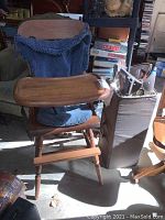 Vintage wooden high chair with blue fabric covers and removable tray next to a fabric foldable pack-and-play playpen.
