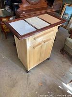 Kitchen cart showing natural wood finish with drawer and two cabinet doors on wheels.