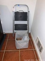 Full view of 2-step ladder with fabric basket beneath it showing overall size and shape.