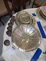 Group view of six shot cups and large round hammered bowl on lace cloth