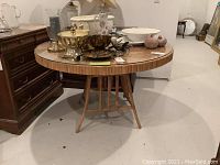 Round bamboo table shown fully, with various items on top not included in the lot.