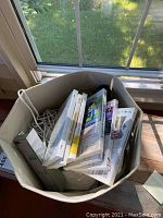 Bin containing several white Nintendo Wii game cases including Mario Kart, The Legend of Zelda: Twilight Princess, and Donkey Kong Country Returns.