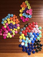 Overview of all buttons sorted by color, showing variety in size and color on a wooden surface.