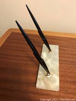 Marble base with two black pens angled, showing color and finish of base and pens