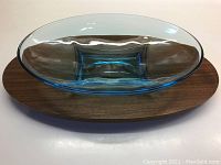 Top view showing the teak tray with the turquoise Hazel Atlas glass bowl fitted inside. Bowl has a smooth oval shape with inset square base. Teak tray is oval with smooth finish and some minor dents.