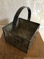 Overall image showing square woven silver plate basket with thick handle and visible tarnish.